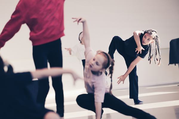 Kinderen bewegen in verschillende poses tijdens dansles in lichte studio
