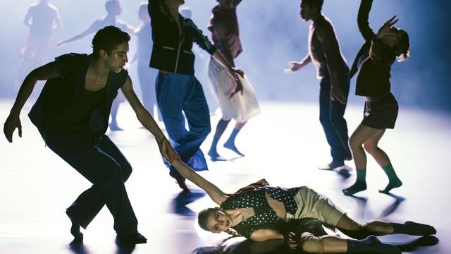 Dansers in expressieve poses; Eliana Hayward op de grond, hand in hand met Justin Padilla, intense sfeer, moderne dans, emotie, samenwerking